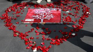 Pictures of the 43 missing students are displayed inside a heart shape made out of rose petals on the pavement in Mexico City
