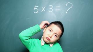 Niño frente a una pizarra con una cuenta matemática.