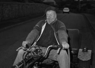 A man riding a motorbike with an expression of glee