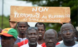 Protestors march holding a placard they take part in a rally "no to barbarism" in central Ouagadougou on August 19, 2017, after a recent attack in the capital of Burkina Faso in which 18 people were killed. Gunmen killed nine locals and nine foreigners as they dined on the terrace of a Turkish restaurant in Ouagadougou late August 13.