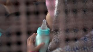 Маленький ребенок ждет распределения в лагерь для детей мигрантов