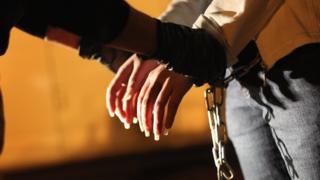 Una mujer que deportan de Estados Unidos es esposada por las autoridades.