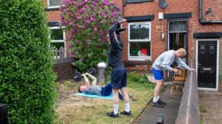 Männer benutzen Fitnessgeräte in einem Garten