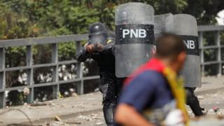 Policías apuntan a un manifestante