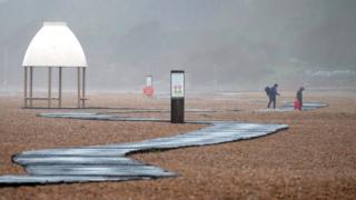 People walk along the beach in Folkestone, Kent