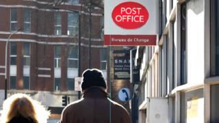 People walking past Post Office sign