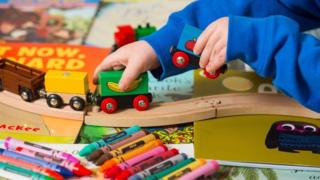 Ребенок играет с деревянным набором поездов