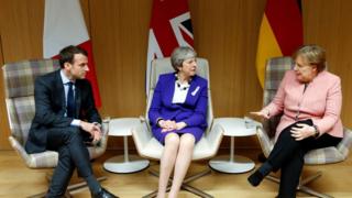 Umukuru w'Ubufaransa Emmaneul Macron (i bubamfu), umushikiranganji wa mbere w'Ubwongereza Theresa May (hagati) n'umuchanceliere w'Ubudage Angela Merkel