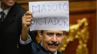 A Venezuelan opposition deputy holds up a sing reading " Maduro dictator" during an extraordinary session of the National Assembly, in Caracas on October 23, 2016.