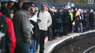 Commuters wait on a railway platform