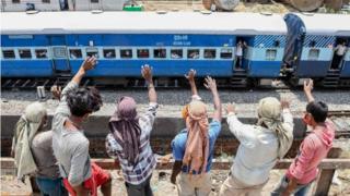 Arbeiter, die auf einer Welle am Straßenrand stehen, für Wanderarbeiter und Familien, die in einem Sonderzug von Amritsar nach Barauni im Bundesstaat Bihar sitzen, als sie am 10. Mai 2020 in ihre Heimatstädte zurückkehren, nachdem die Regierung eine landesweite Sperrung gelockert hat