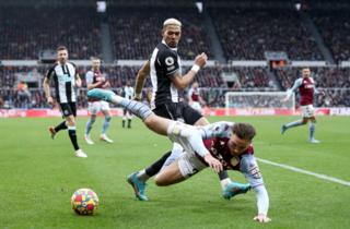 Joelinton challenges Matty Cash for the ball