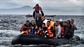 Мужчина задерживает маленького мальчика, когда лодка с мигрантами и беженцами прибывает на греческий остров Лесбос после пересечения Эгейского моря из Турции 21 октября 2015 года