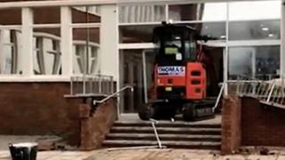 Экскаватор разламывает двери в отель