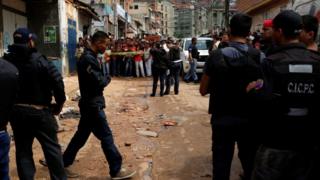 Сотрудники полиции и следователи по уголовным делам ищут доказательства перед пекарней, после того, как она была разграблена в Каракасе