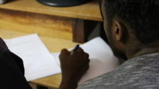 Haitiano sentado perto de documentos sendo assinados