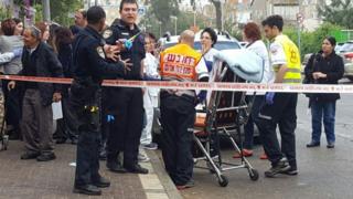 Officers pass on a handheld lighter outside the Clalit HMO clinic in Holon