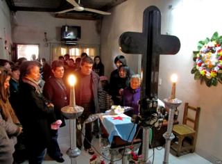 Varias personas están en un cuarto pequeño en medio de una ceremonia religiosa.