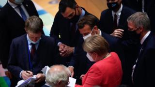 German Chancellor Angela Merkel (C, down) speaks with French President Emmanuel Macron (C) and Spanish Prime Minister Pedro Sanchez (C, up) during a round table meeeting at an EU summit over a post-virus economic rescue plan in Brussels, on July 20, 2020.