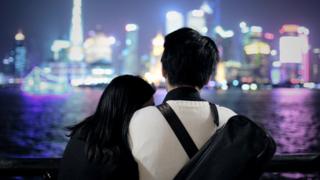 A couple look out at a cityscape