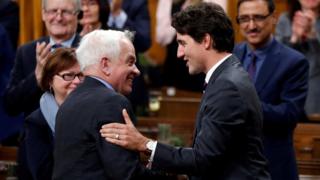Премьер-министр Канады Джастин Трюдо (справа) пожимает руку бывшему министру иммиграции Джону МакКаллуму