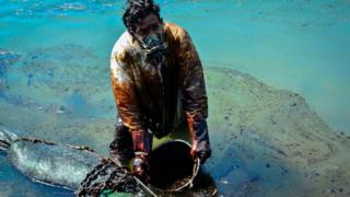 Man clearing oil slick from beach