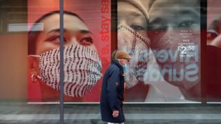 Мужчина проходит мимо рекламы масок для лица в Сандерленде
