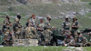 Indian army soldiers rest next to artillery guns at a transit camp before heading to Ladakh, 16 June