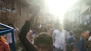 A screen grab from the video where a woman is being paraded surrounded by a mob