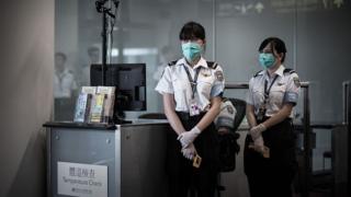 Airport personnel wait for passengers to check their temperature as part of preventive measures against the spread of Middle East Respiratory Syndrome (MERS) at the Hong Kong international airport on June 5, 2015.