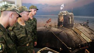 Marinos rusos frente a una fotografía del submarino Kursk.