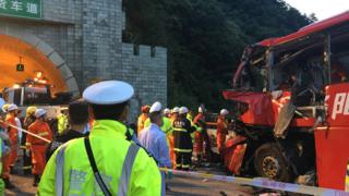 Police and firefighters work near the wreckage of a coach in Shaanxi province, 11 August