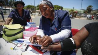 Nurses check the blood pressure of a woman.