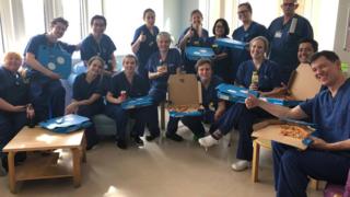 NHS workers in blue uniform with pizza