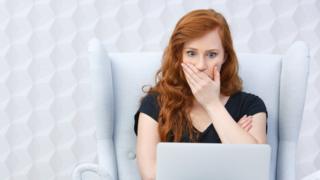 mujer con gesto de sorpresa mirando laptop