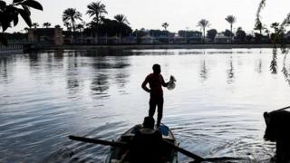 صياد يقف فوق قارب صيد وسط النهر