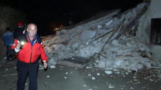 People walk past rubble as rescue operations begin in Villa Sant'Antonio village, near Visso, Marche region, Italy, on 26 October 2016