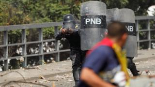 Agente da Polícia Nacional atira balas de borracha contra manifestantes anti-Maduro em Caracas, em 23 de janeiro de 2019