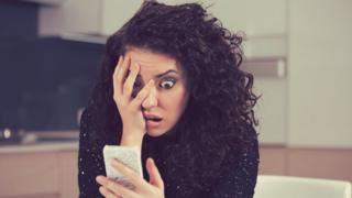 Mujer asustada mirando celular