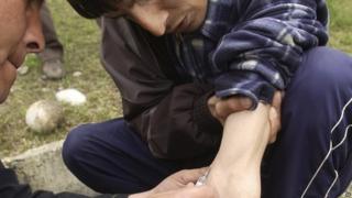 A Kyrgyz drug addict delivers a heroin injection to another drug addict in Osh, southern Kyrgyzstan (March 2005)