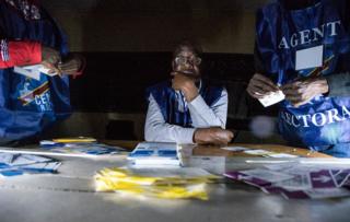 Independent National Electoral Commission (CENI) agents count votes during an electricity cut while watched by observers at Kiwele college in Lubumbashi on December 30, 2018