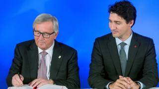 President of the European Commission Jean-Claude Juncker signs the Comprehensive Economic and Trade Agreement (CETA) as Canadian Prime Minister Justin Trudeau looks on at the European Council in Brussels on 30 October 2016.