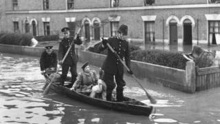 Policemen rowing down a street in the 1947 London floods