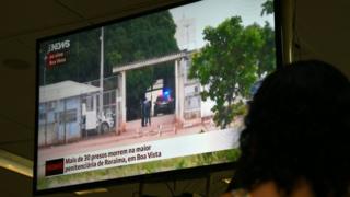 A woman watches on television news about the riot in the PAMC (Agricola de Monte Cristo Penitentiary) in Roraima, northern Brazil