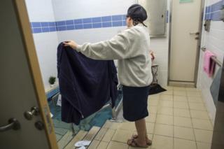 A Balanit, or mikveh attendant holds a towel for a Jewish woman that entered the water of a mikveh in Jerusalem on April 17,2019. (Photo by Heidi Levine for The BBC).