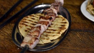 Photo shows a skewer of grilled souvlaki on pita bread at a kebab-souvlaki restaurant in the Monastiraki district of Athens