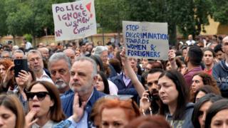 Demonstrators holding up placards at a vigil in memory of the the victims of the serial killer in Nicosia on April 26