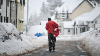 Post man delivering post in the snow.