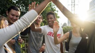 Grupo de adolescentes bate palmas e sorri