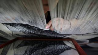 Marta Soria, 34, checks her work on a mirror as she hand-weaves a tapestry on a centuries-old loom at the Royal Tapestry Factory